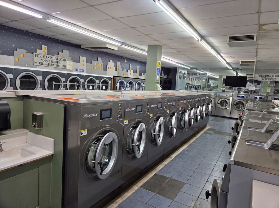 Kingstar washers and dryers lining a busy retail laundromat floor